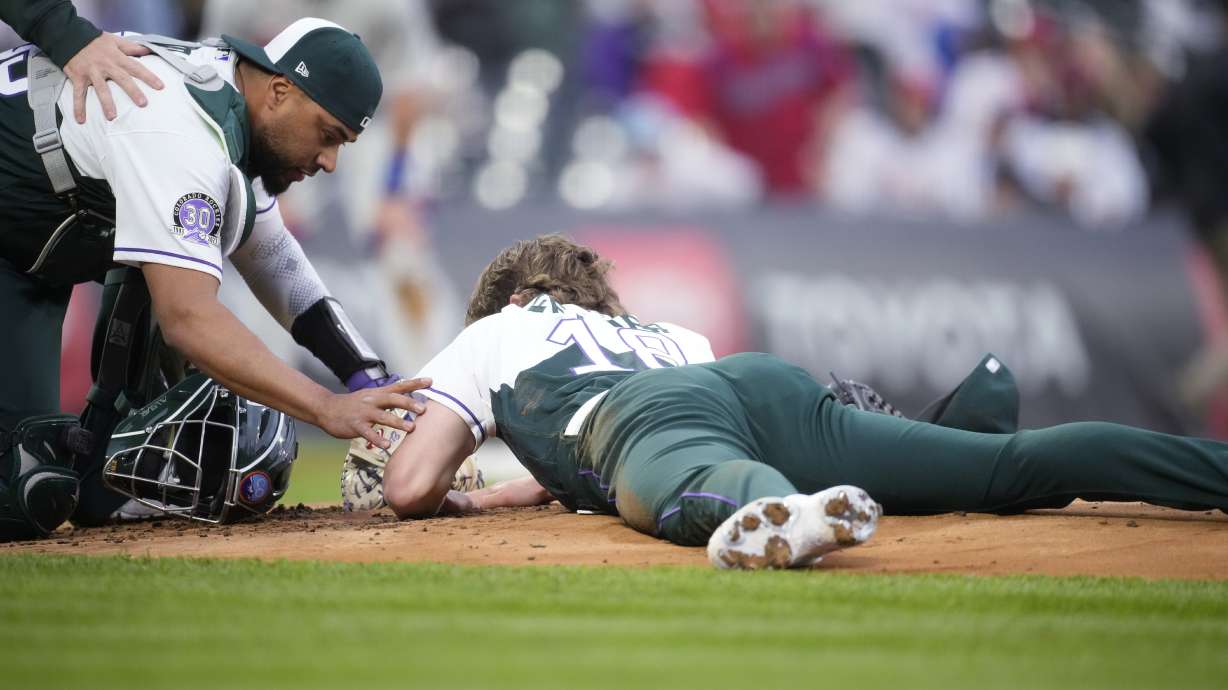 Colorado Rockies catcher Elias Diaz, left, checks on starting pitcher Ryan Feltner, who lies on the mound after getting hit by a single off the bat of Philadelphia Phillies' Nick Castellanos during the second inning of a baseball game Saturday, May 13, 2023, in Denver.