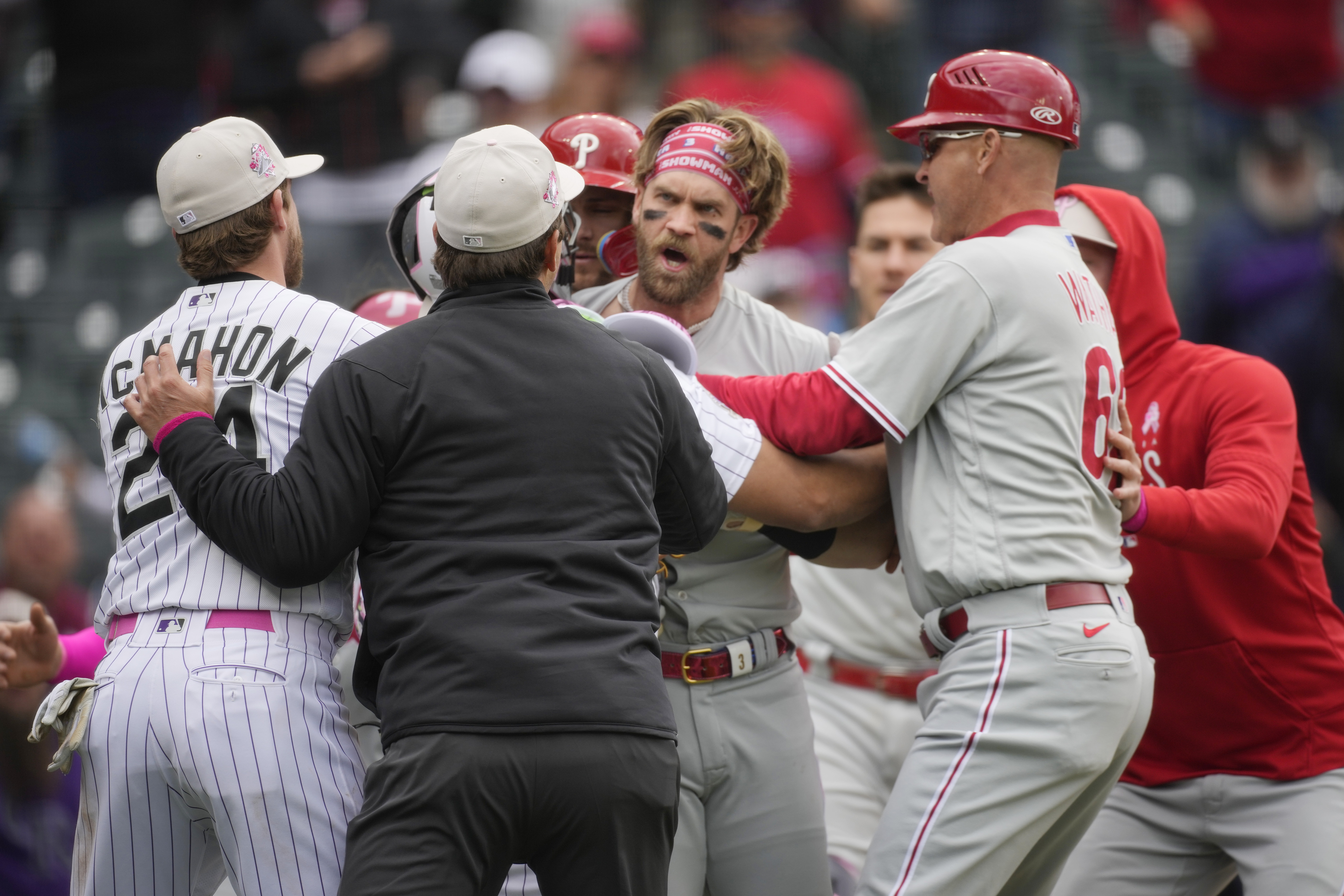 Philadelphia Phillies designated hitter Bryce Harper, back center, is held back from pursuing Colorado Rockies relief pitcher Jake Bird by, from front left, Colorado's Ryan McMahon, first base umpire Ben May and Philadelphia third base coach Dusty Wathan in the seventh inning of a baseball game, Sunday, May 14, 2023, in Denver. 
