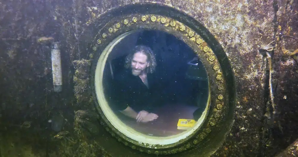 Dr. Joseph Dituri peers out of a large porthole, Saturday at Jules' Undersea Lodge positioned at the bottom of a 30-foot-deep lagoon in Key Largo, Fla. Dituri broke a record for the longest time living underwater at ambient pressure.
