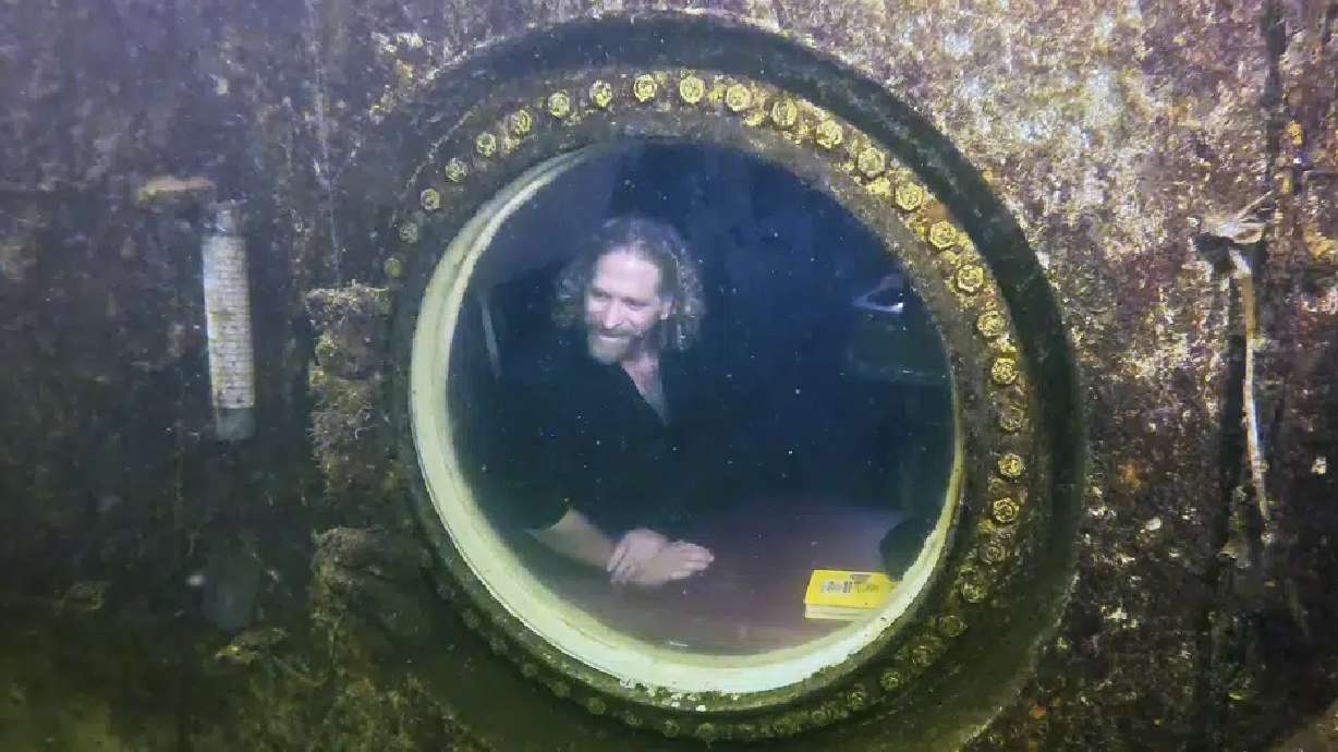 Dr. Joseph Dituri peers out of a large porthole, Saturday at Jules' Undersea Lodge positioned at the bottom of a 30-foot-deep lagoon in Key Largo, Fla. Dituri broke a record for the longest time living underwater at ambient pressure.