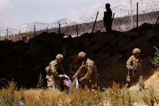 Members of the Texas Army National Guard extend razor wire to inhibit migrants from crossing, as seen from Ciudad Juarez on Saturday.