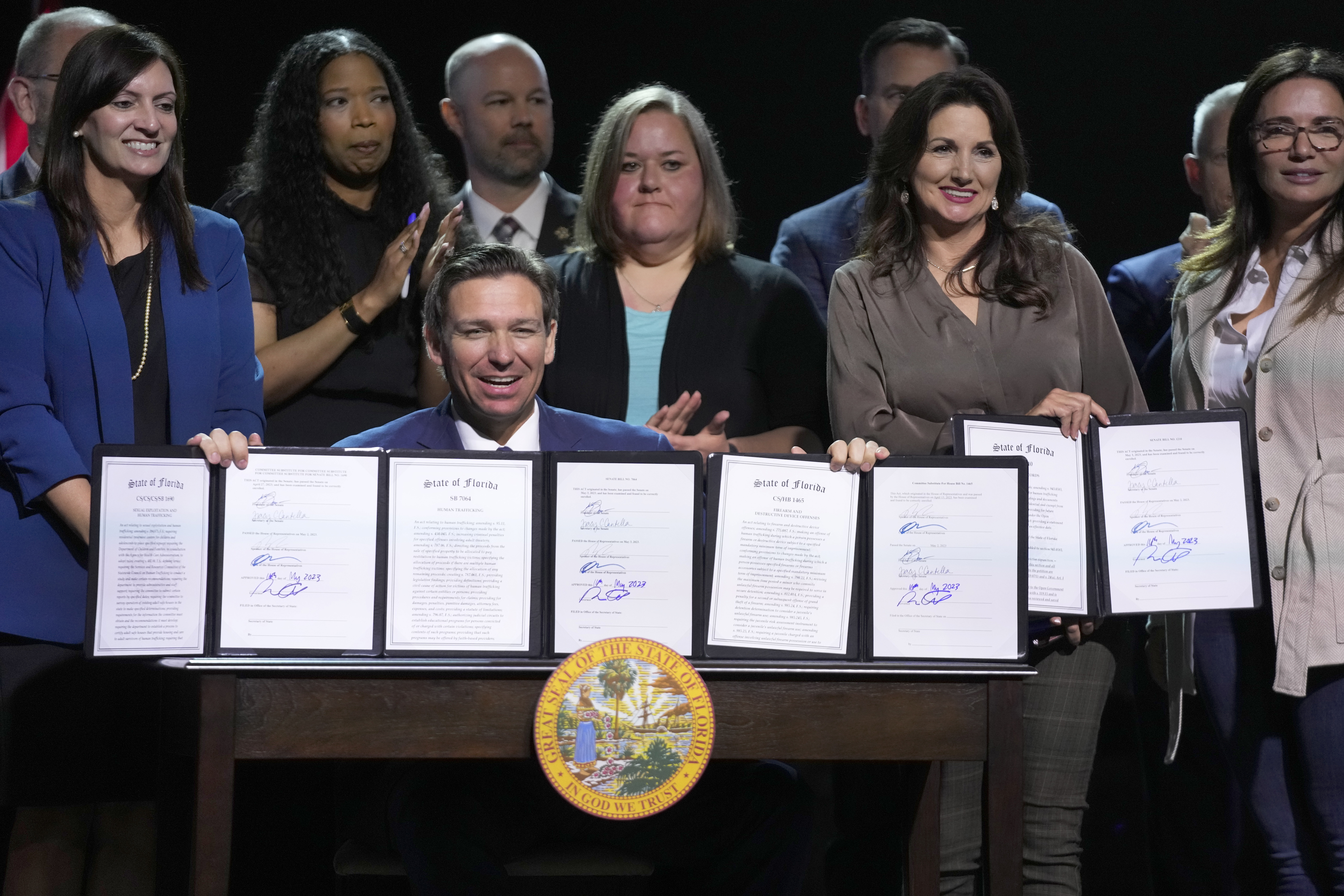 Florida Gov. Ron DeSantis holds up bills he signed during a bill signing ceremony at the Coastal Community Church at Lighthouse Point, Tuesday, in Lighthouse Point, Fla. Florida is banning transgender-related treatment for minors.