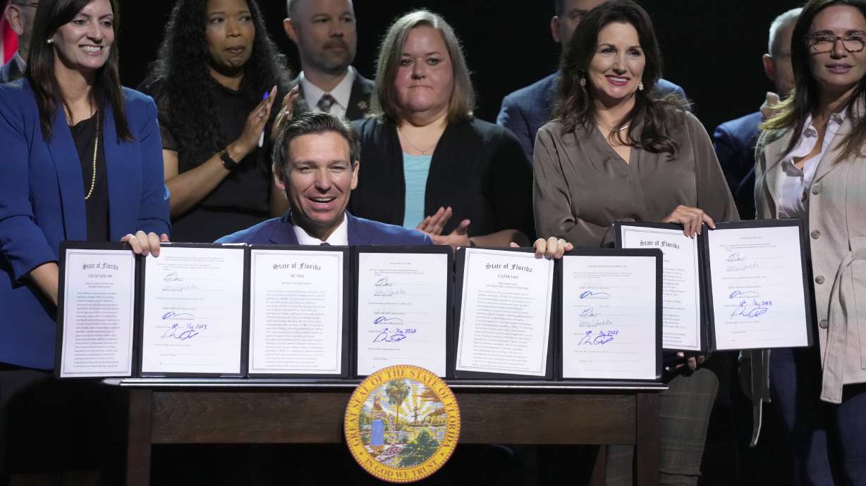 Florida Gov. Ron DeSantis holds up bills he signed during a bill signing ceremony at the Coastal Community Church at Lighthouse Point, Tuesday, in Lighthouse Point, Fla. Florida is banning transgender-related treatment for minors.