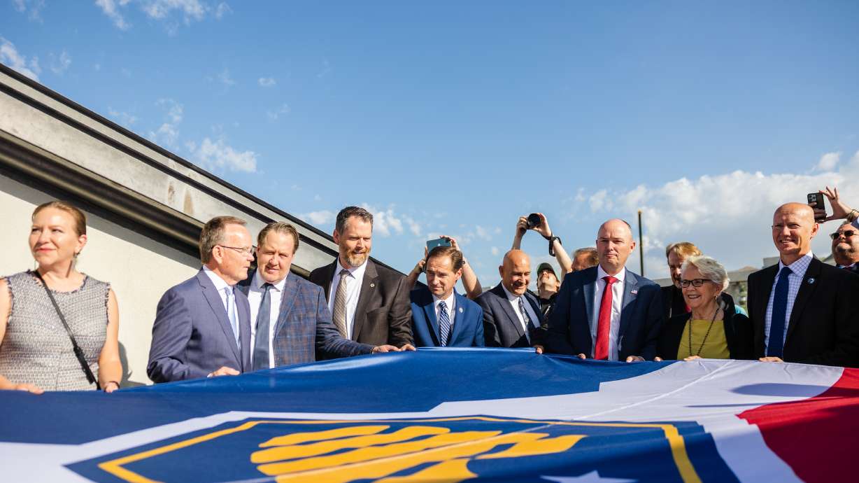 State officials, including Utah Gov. Spencer Cox and Senate President Stuart Adams, R-Layton, hold the flag during the raising of the new Utah state flag at the Capitol in Salt Lake City on Wednesday.