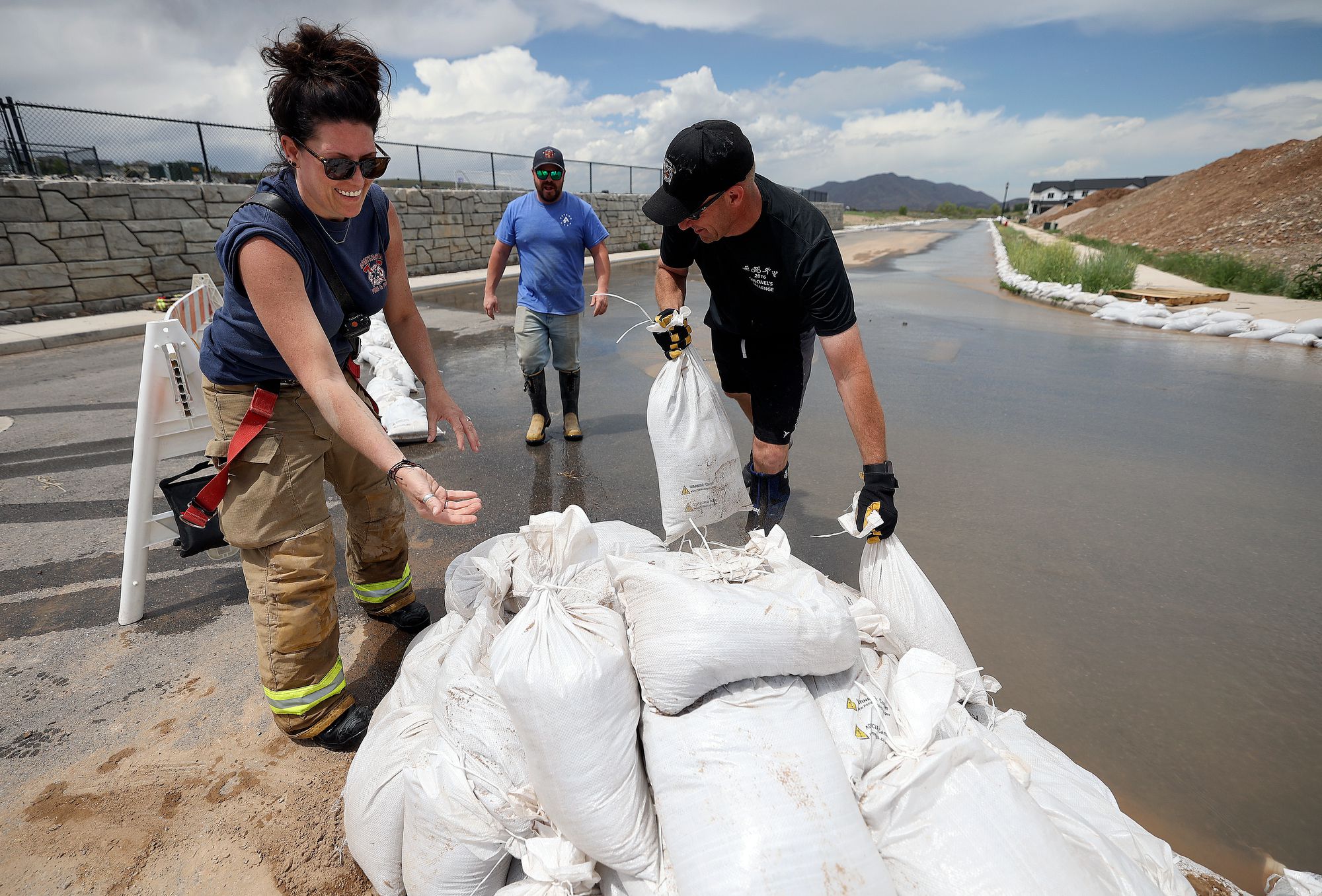 Santaquin firefighters Amber Cummings, Capt. Kyle Pace and Capt. Corey Houskeeper set up sandbags to contain flooding in Santaquin on Wednesday. In a special session, lawmakers addressed issues like funding firefighting and flood control.