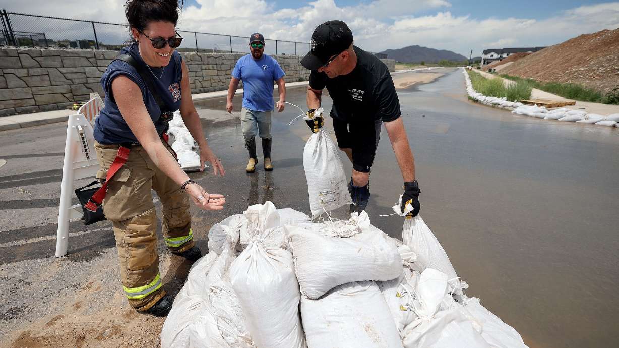 Santaquin firefighters Amber Cummings, Capt. Kyle Pace and Capt. Corey Houskeeper set up sandbags to contain flooding in Santaquin on Wednesday. In a special session, lawmakers addressed issues like funding firefighting and flood control.