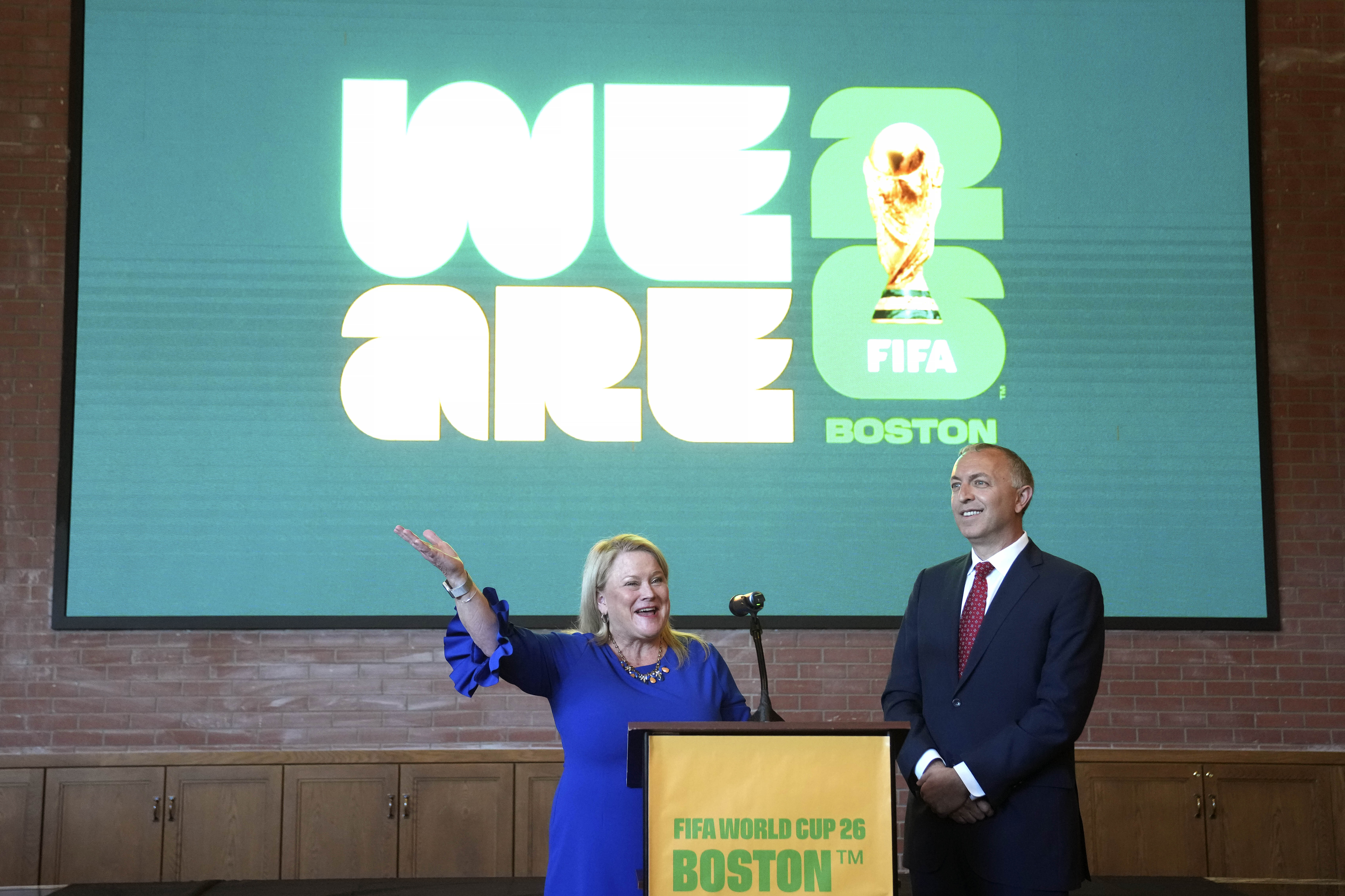 Martha J. Sheridan, President and CEO, Meet Boston, left, and Brian Bilello, President of Boston Soccer 2026, and the New England Revolution, right, stand in front of a projection of a logo as part of Boston Soccer 2026's local branding for the 2026 World Cup, during ceremonies, Thursday, May 18, 2023, in Boston. Gillette Stadium in Foxborough, Mass., is one of 16 venues in the United States, Mexico and Canada tapped to host soccer matches for the international sporting event. 