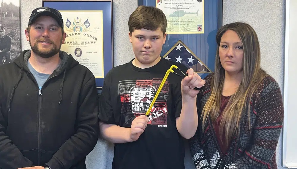 Andrew Burns, left, Owen Burns, center, and Margaret Burns pose with a slingshot Owen used to thwart an alleged kidnapping attempt of his sister, on Wednesday in Alpena Township, Mich. 