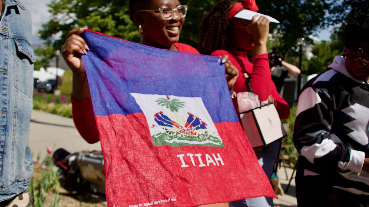 Audience members fly the Haitian Flag during a Haitian Flag Day Ceremony at Washington Square in Salt Lake City on Thursday.