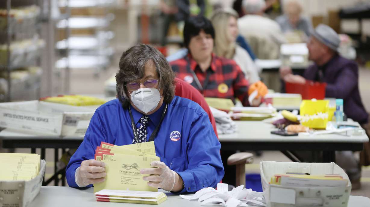 Jerry Schmidt rips off ballot signature tabs in the Salt Lake County Clerk’s ballot processing room on Election Day on Nov. 8, 2022. State lawmakers have begun to explore additional legal protection for election workers.