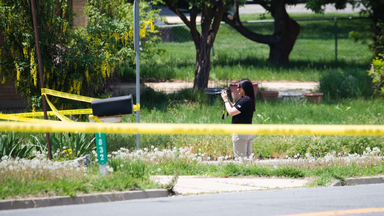 A crime scene investigator photographs the scene of what police say is a triple homicide in Layton on Friday.