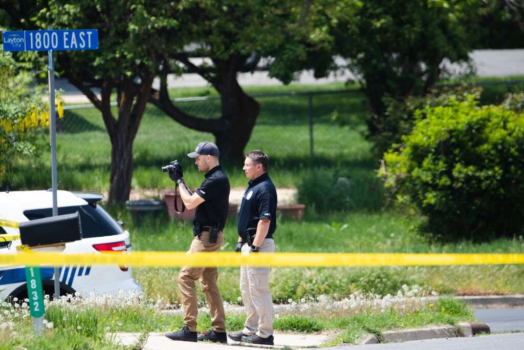 Layton police officers photograph a home and yard at the scene of a triple homicide in Layton on Friday.