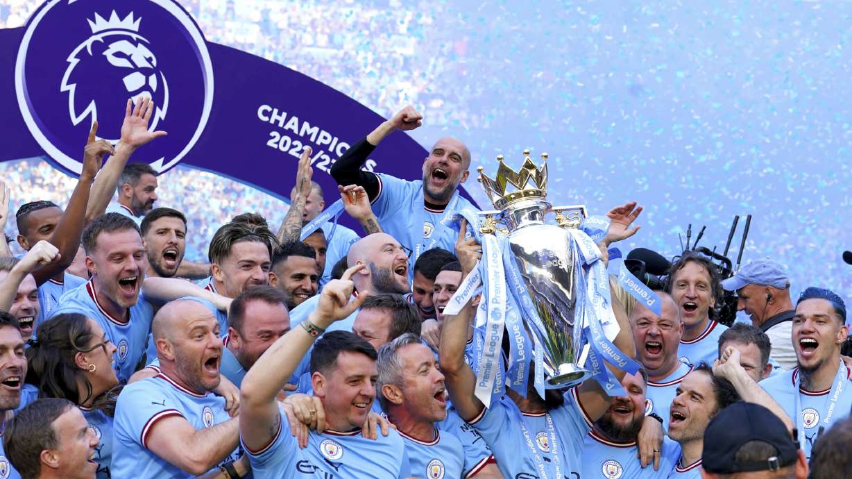 Manchester City players and staff including Pep Guardiola celebrate with the Premier League trophy after their English Premier League title win at the end of the English Premier League soccer match between Manchester City and Chelsea at the Etihad Stadium in Manchester, England, Sunday, May 21, 2023.