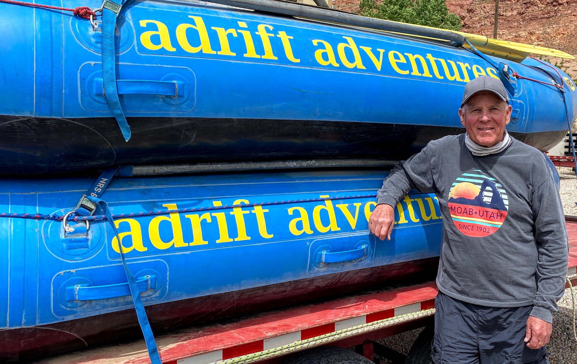 Myke Hughes, owner of Adrift Adventures in Moab, poses with two of his rafts.