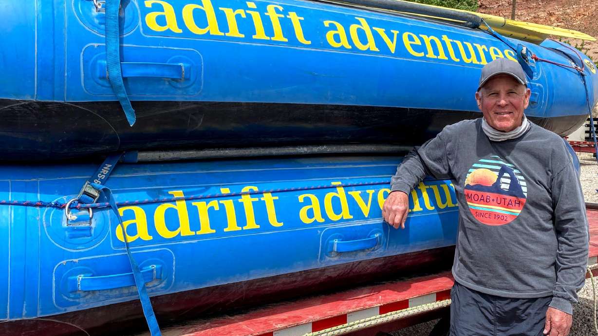 Myke Hughes, owner of Adrift Adventures in Moab, poses with two of his rafts.