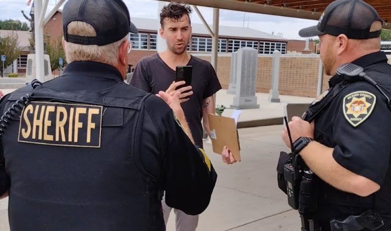 Direct Action Everywhere advocate Curtis Vollmar is seen speaking with Beaver County sheriff deputies on the sidewalk outside Main Street Park, Beaver on July 23, 2022.