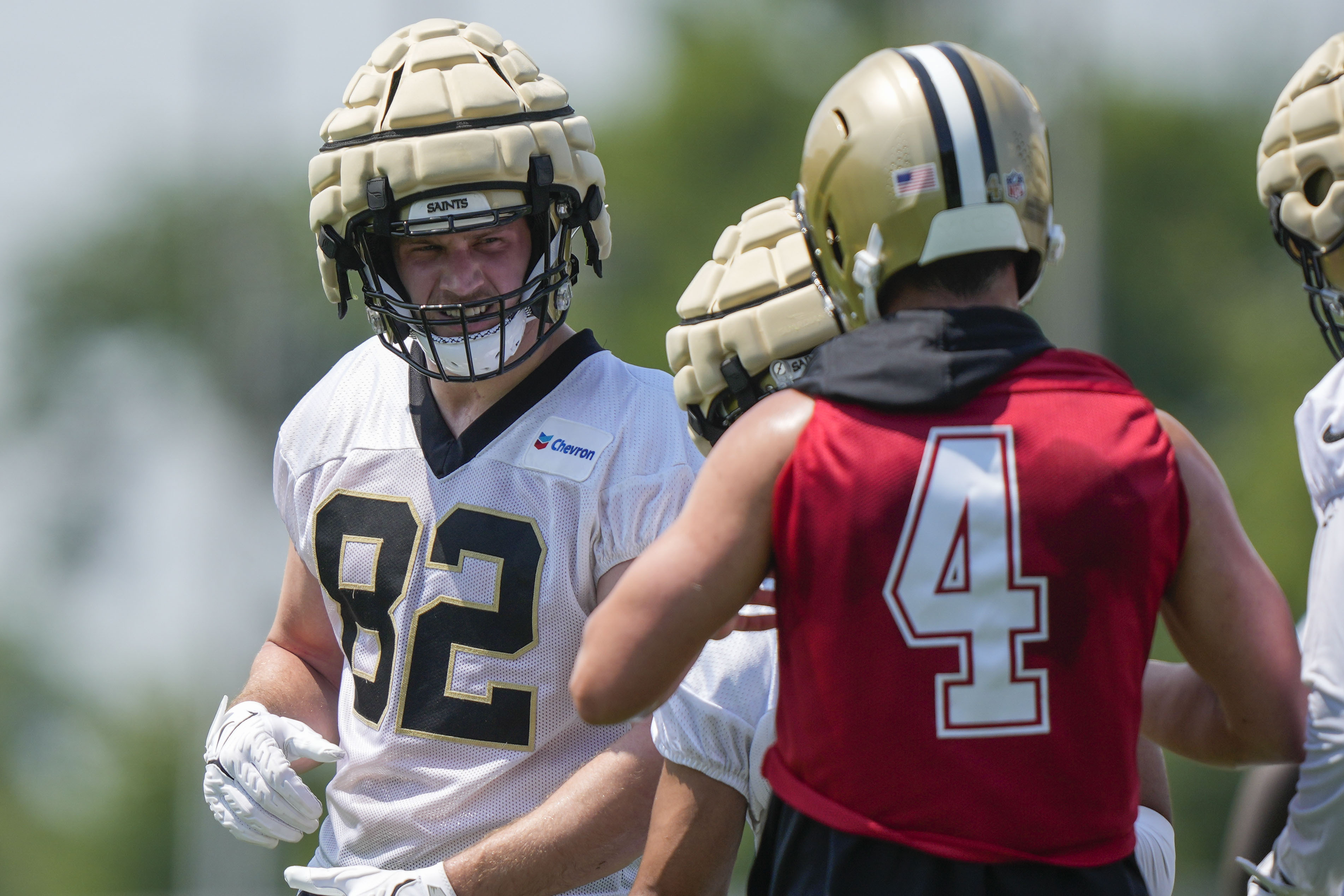 New Orleans Saints tight end Foster Moreau (82) talks with quarterback Derek Carr (4) during NFL football practice in Metairie, La., Tuesday, May 23, 2023. 