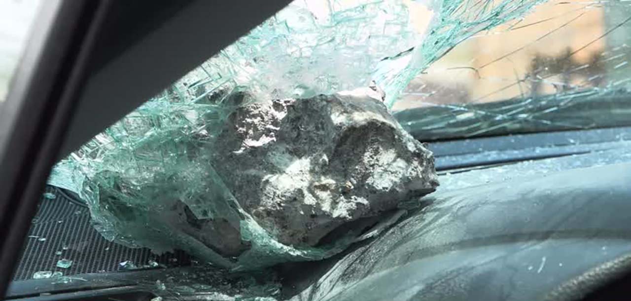 A rock sits on the dashboard of Sam Fairbourn's car after he says the rock hit his car's windshield as he drove on I-215 Monday.