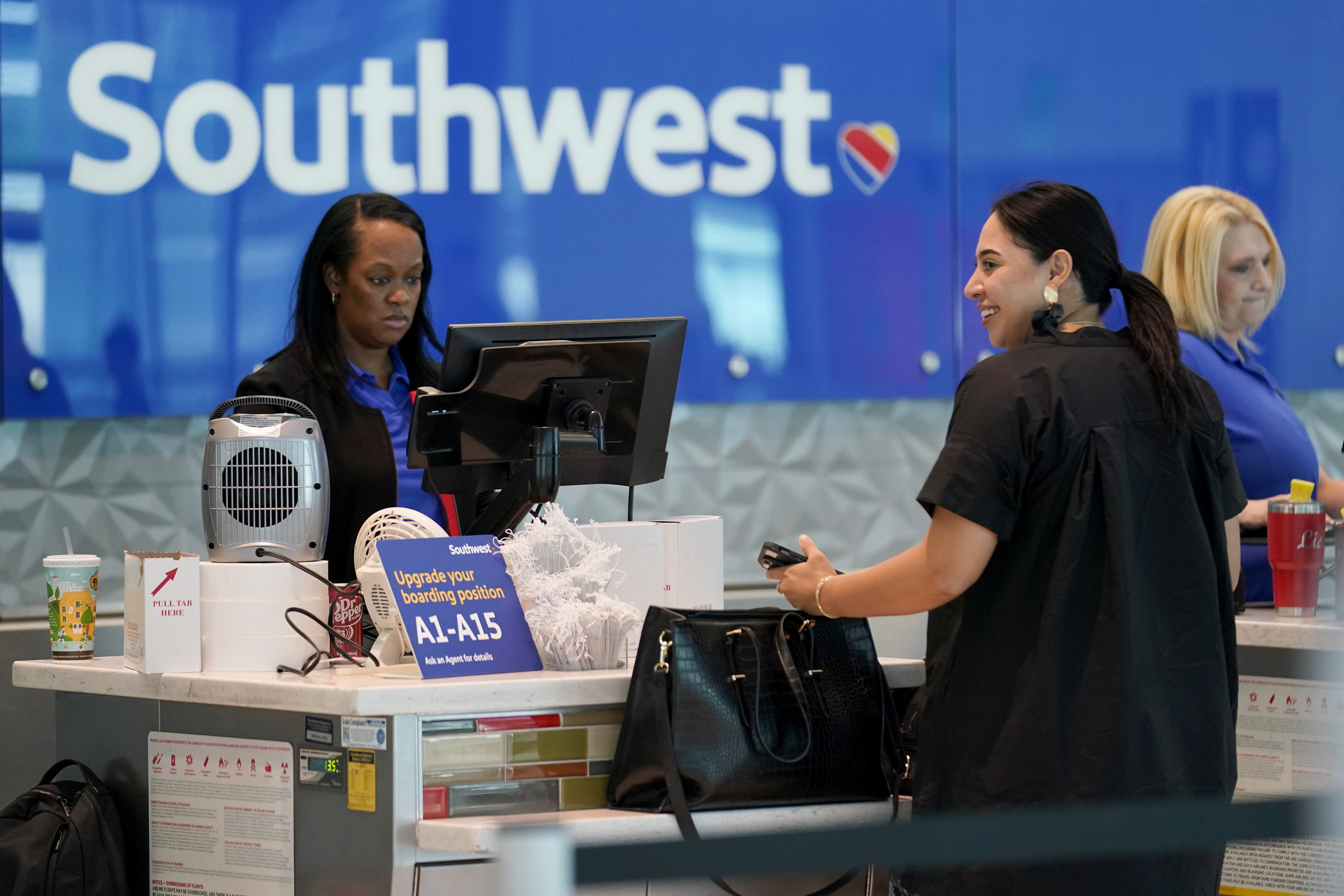 A Southwest Airlines customer service representative, left, assists a traveler at the ticketing counter at Love Field airport, Friday in Dallas. The unofficial start of the summer travel season is here, with airlines hoping to avoid the chaos of last year.