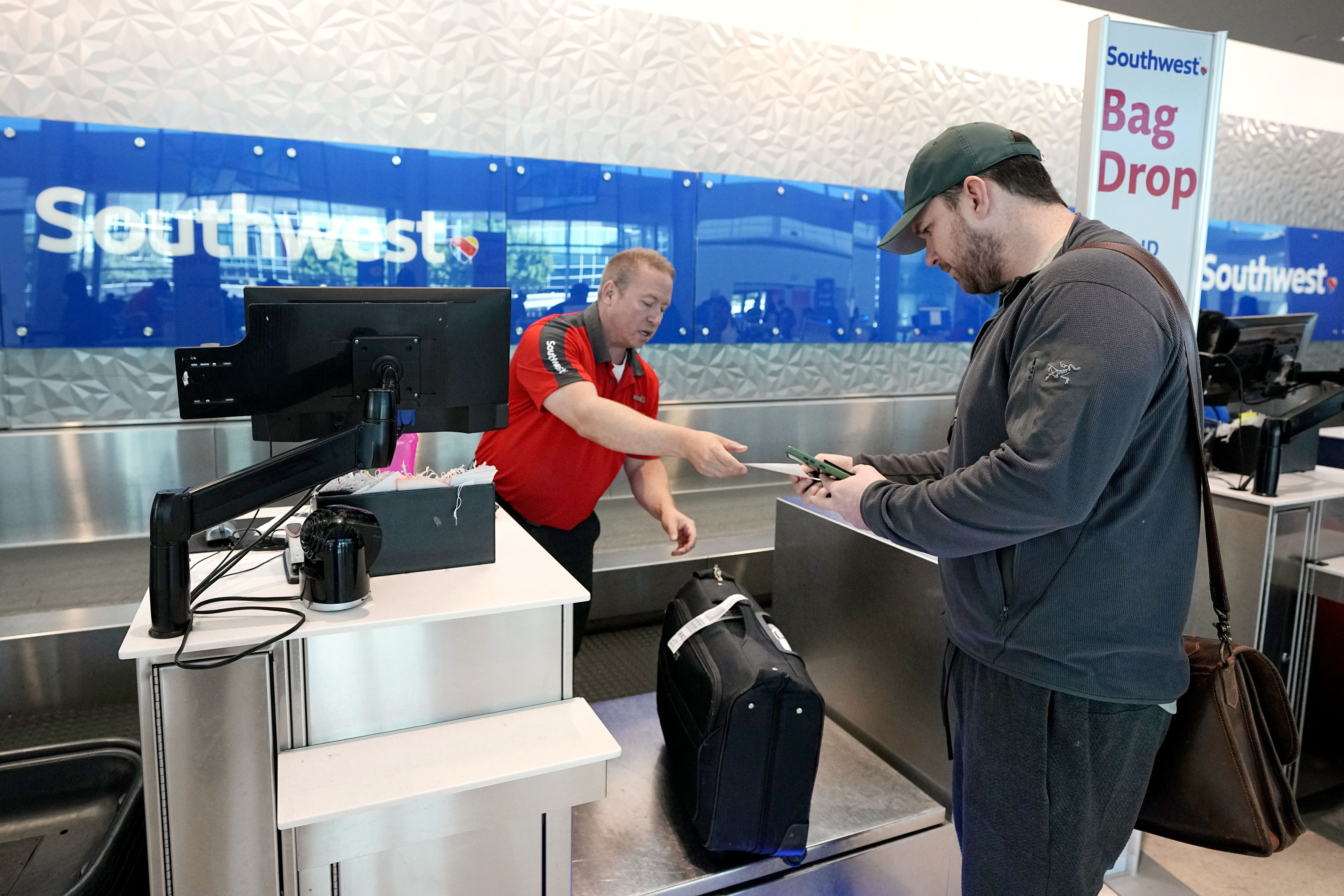 Chris Odom, right, checks his bags with a customer service representative at the Southwest ticketing gate at Love Field airport, May 19, in Dallas. The unofficial start of the summer travel season is here, with airlines hoping to avoid the chaos of last year.
