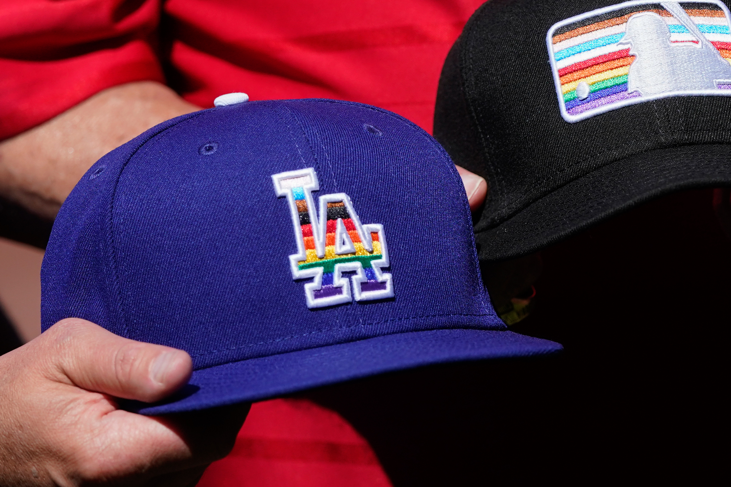 Los Angeles Dodgers senior vice president of marketing, communications and broadcasting, Erik Braverman, holds a hat while posing for photos on Pride Day at Oracle Park before a baseball game between the Giants and the Dodgers in San Francisco, Saturday, June 11, 2022.