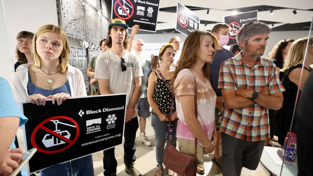 Emily Warner, left, holds a sign protesting a Little Cottonwood Canyon gondola during a Wasatch Front Regional Council meeting in Salt Lake City on Thursday. Despite opposition, the council voted to pass the plan with the gondola included.