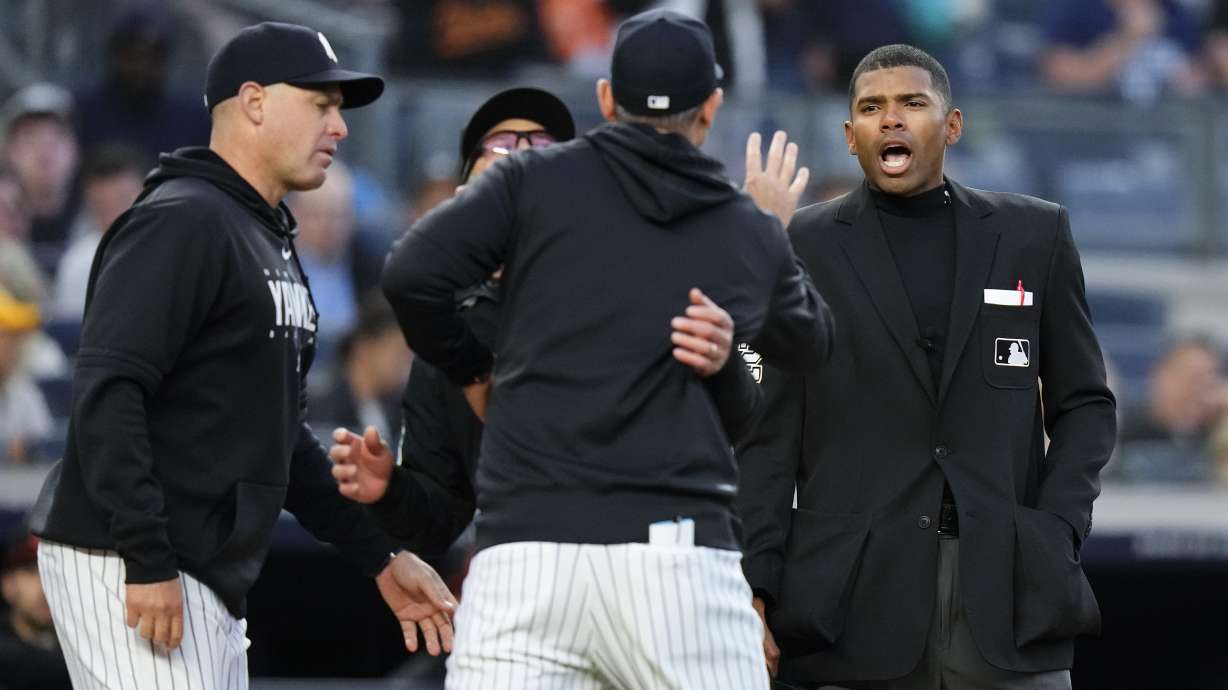 Home plate umpire Edwin Moscoso, right, talks to New York Yankees manager Aaron Boone as Boone is restrained after being ejected during the third inning of the team's baseball game against the Baltimore Orioles on Thursday, May 25, 2023, in New York.