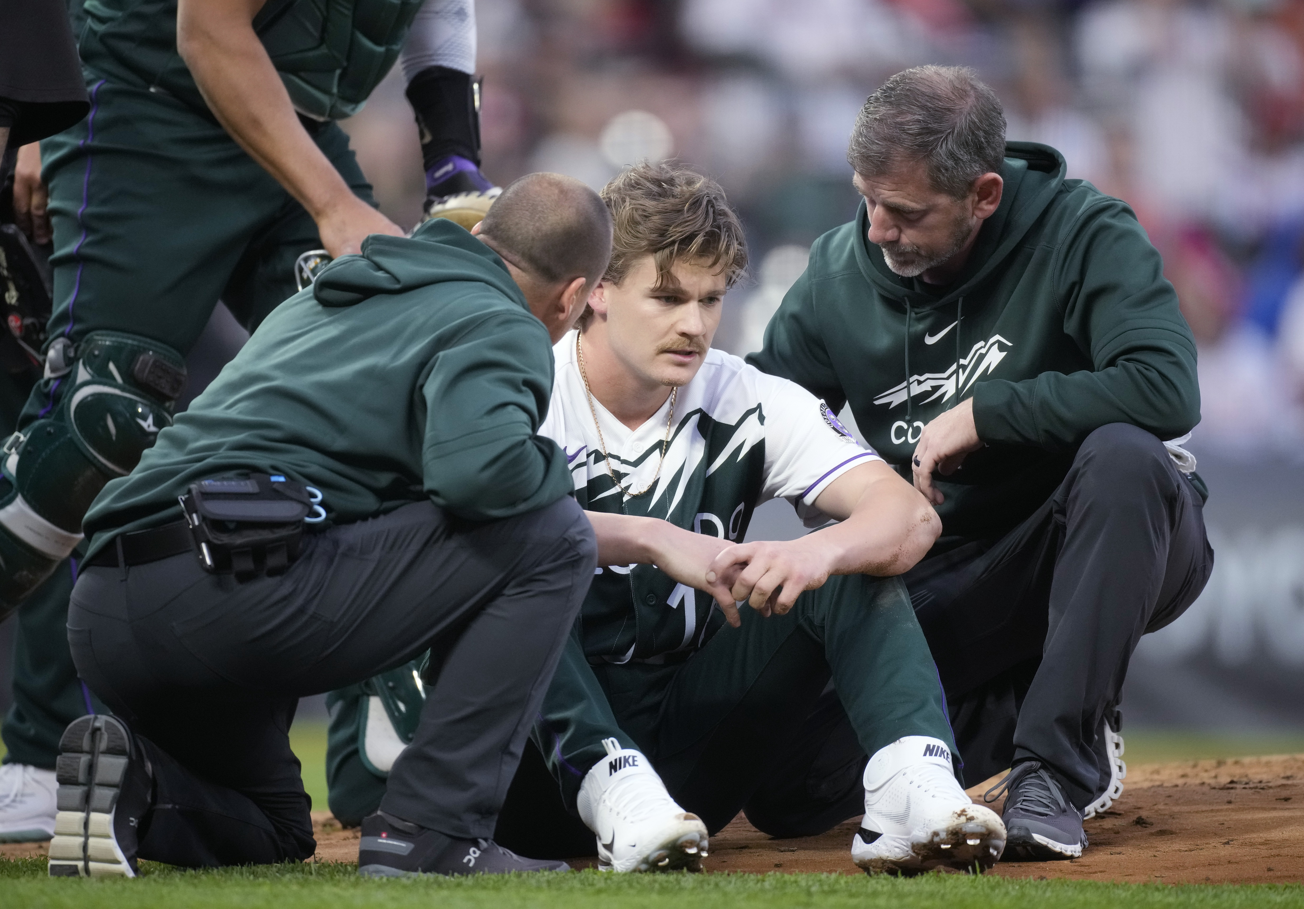 Trainers tend to Colorado Rockies starting pitcher Ryan Feltner after he was hit by a batted ball from Philadelphia Phillies' Nick Castellanos, who singled during the second inning of a baseball game Saturday, May 13, 2023, in Denver. 