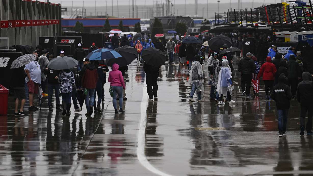 Race fans walk through the garage area while rain causes a delay to a NASCAR Cup Series auto race at Charlotte Motor Speedway Sunday, May 28, 2023, in Concord, N.C.