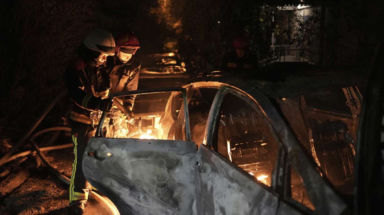 Emergency workers extinguish a fire in a parked car, caused by falling debris from the latest aerial Russian attack in the Pecherskyi district of Kyiv, Ukraine, Tuesday.