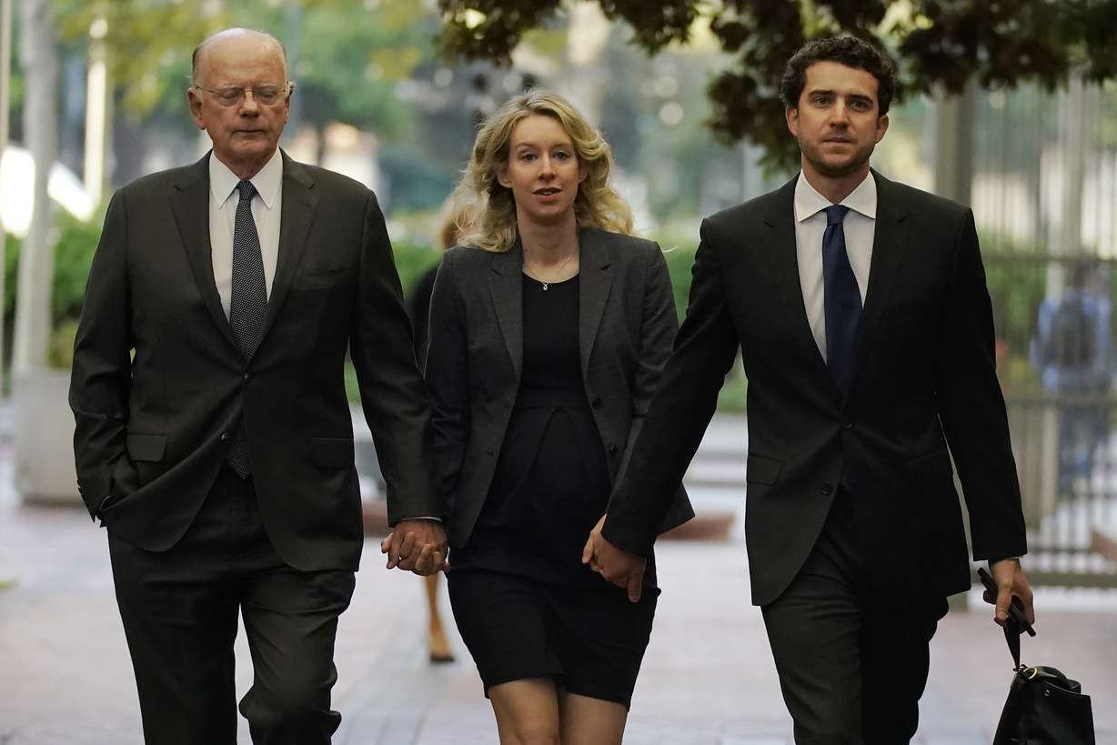 Former Theranos CEO Elizabeth Holmes, center, arrives at federal court with her father, Christian Holmes IV, left, and partner, Billy Evans, in San Jose, Calif., Oct. 17, 2022.