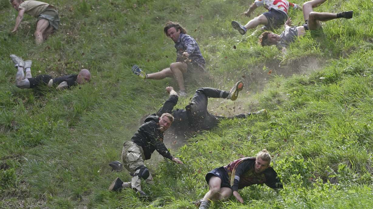 Participants compete in the men's downhill race during the Cheese Rolling contest at Cooper's Hill in Brockworth, Gloucestershire, Monday.