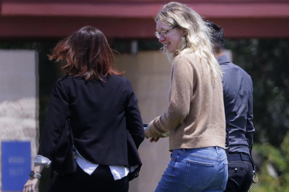 Disgraced Theranos CEO Elizabeth Holmes, center, is escorted by prison officials into a federal women’s prison camp on Tuesday in Bryan, Texas. Holmes will spend the next 11 years serving her sentence for overseeing an infamous blood-testing hoax.