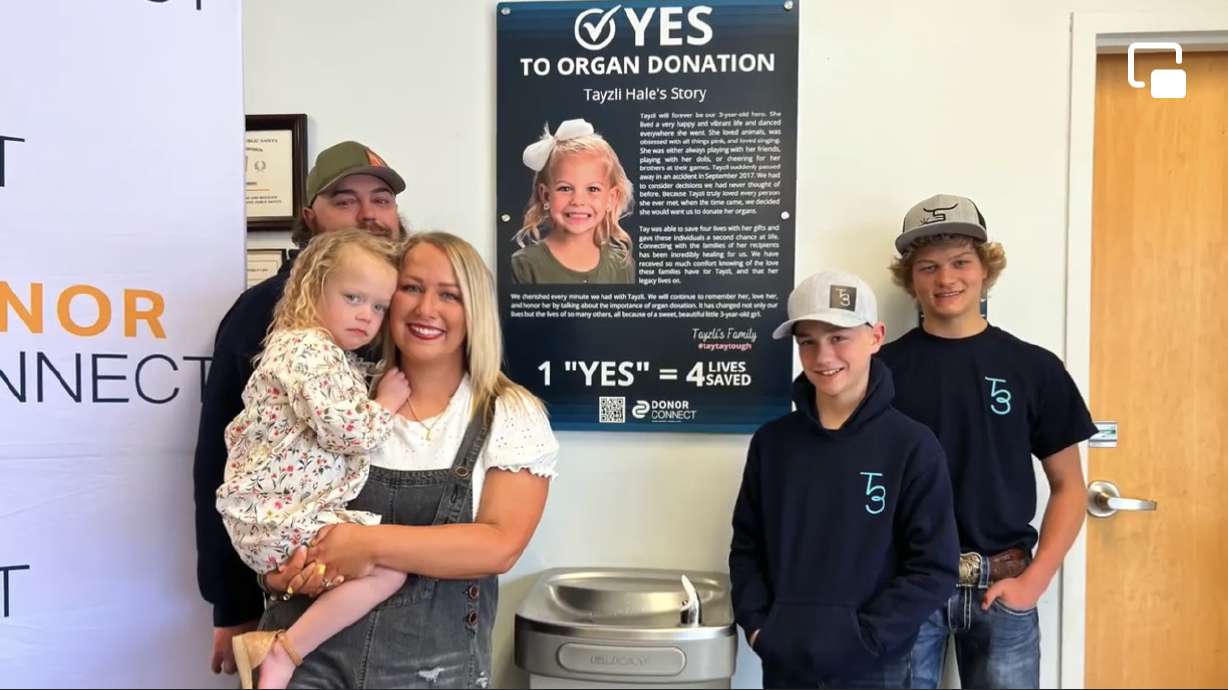 The Hale family stands in front of Tayzli's organ donation plaque at the Utah Driver License Division on April 18 in Logan.