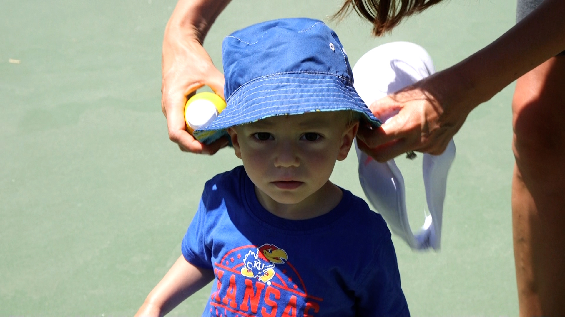 Amanda Jorgensen applies sunscreen and a hat to her child before playing on a sunny day.