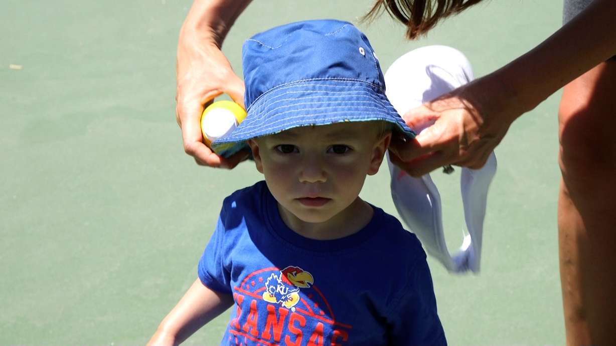 Amanda Jorgensen applies sunscreen and a hat to her child before playing on a sunny day.