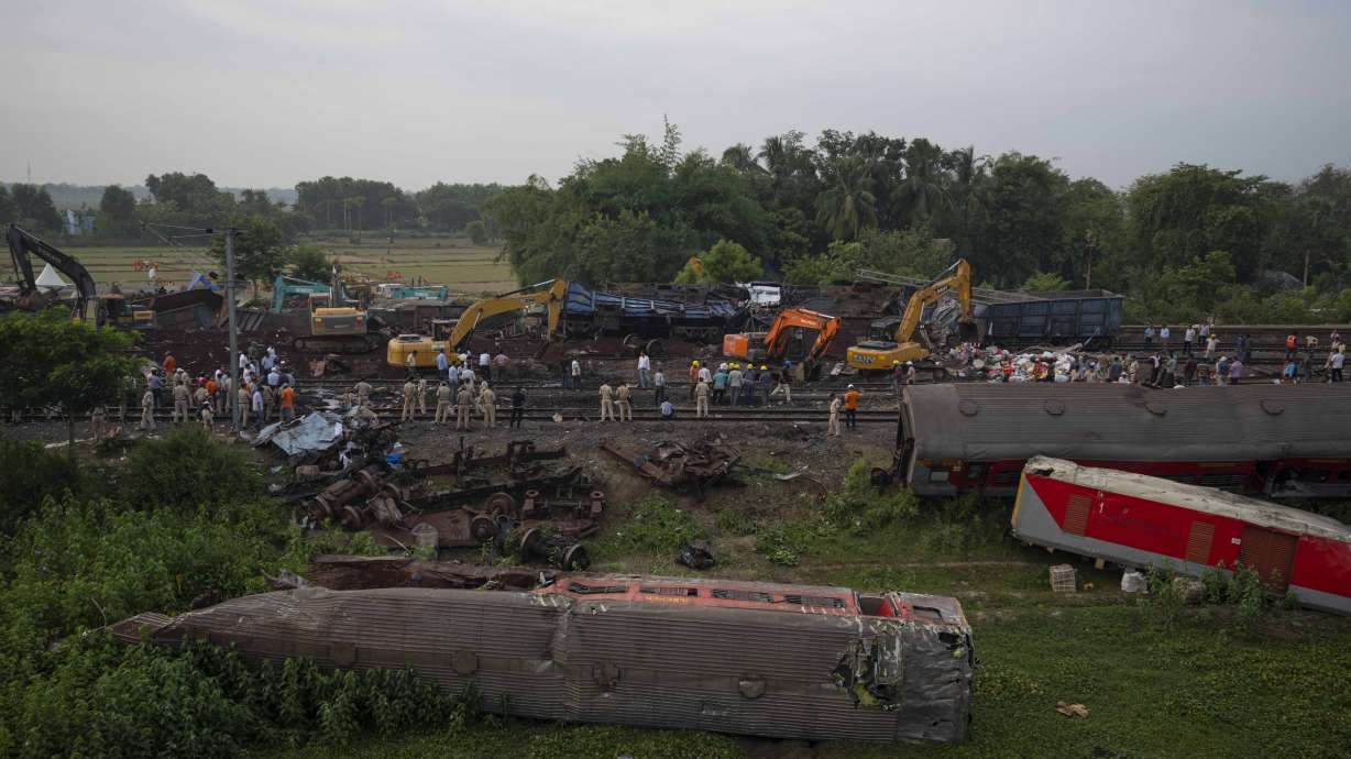 People watch at the site where trains that derailed, in Balasore district, in the eastern Indian state of Orissa, Sunday.