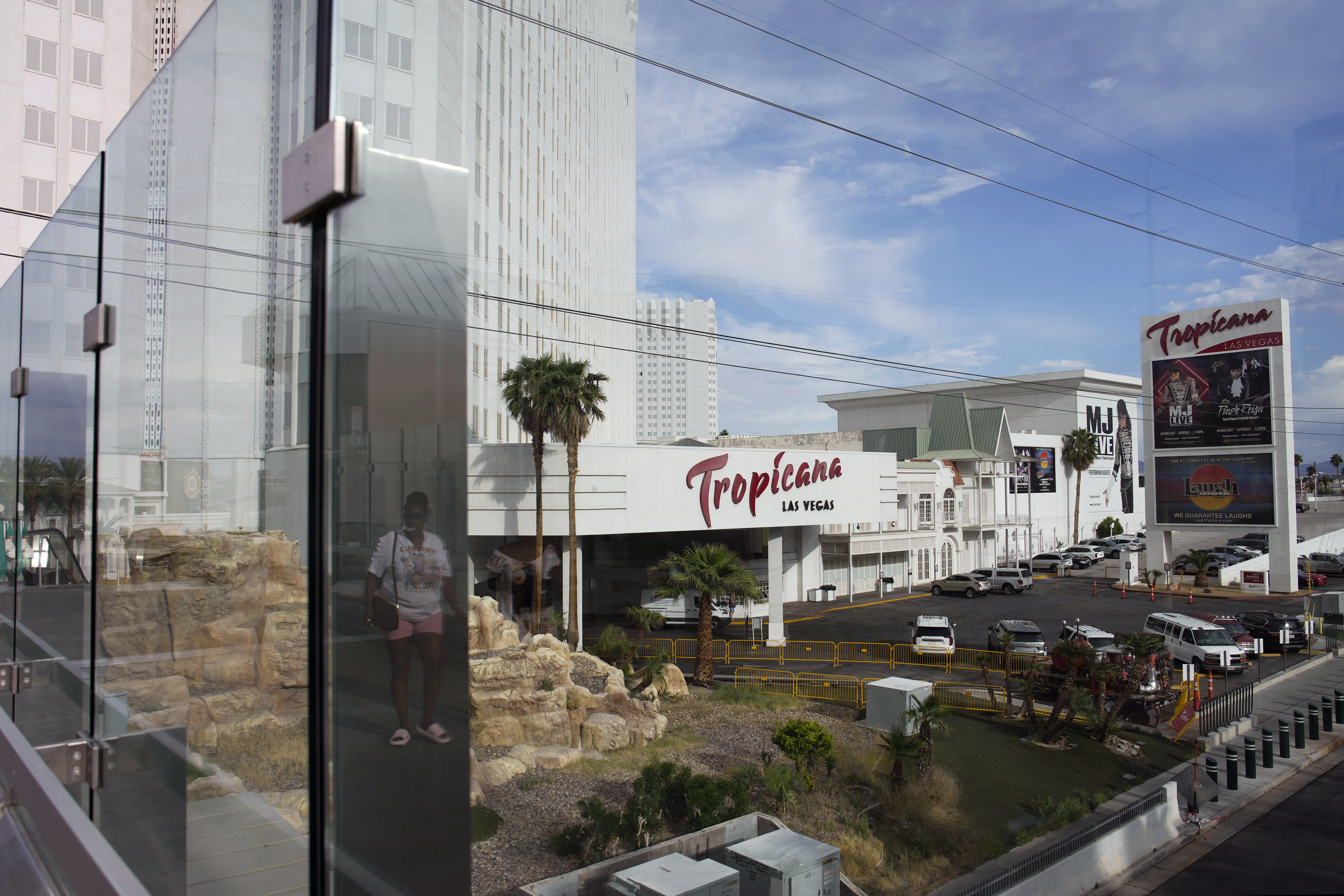 FILE - A person, reflected in glass, walks near the Tropicana Las Vegas on May 16, 2023, in Las Vegas. The proposal to help finance a new Oakland Athletics ballpark, at the Tropicana site, has revived nationwide debates about public funding for private sports clubs, pitting Nevada’s powerful tourism industry against a growing chorus of progressive groups who, throughout the country, are raising concerns about ceding tax revenue that could otherwise be funneled toward government services or schools.
