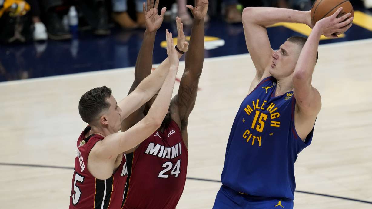 Denver Nuggets center Nikola Jokic, right, shoots over Miami Heat forwards Duncan Robinson, left, and Haywood Highsmith during the first half of Game 1 of basketball's NBA Finals, Thursday, June 1, 2023, in Denver.