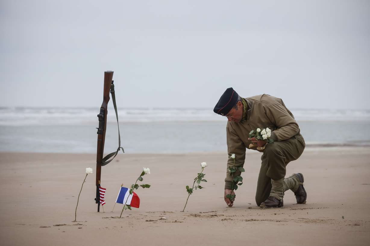 A World War II reenactor plants roses on Omaha Beach in Saint-Laurent-sur-Mer, Normandy, France, Tuesday. The D-Day invasion that helped change the course of World War II was unprecedented in scale and audacity. Nearly 160,000 Allied troops landed on the shores of Normandy at dawn on June 6, 1944.