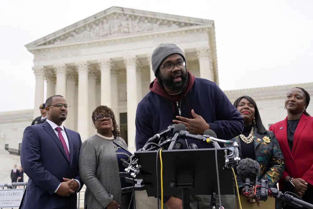 Evan Milligan, center, plaintiff in Merrill v. Milligan, an Alabama redistricting case, speaks with members of the press following oral arguments outside the Supreme Court on Capitol Hill in Washington, Oct. 4, 2022.
