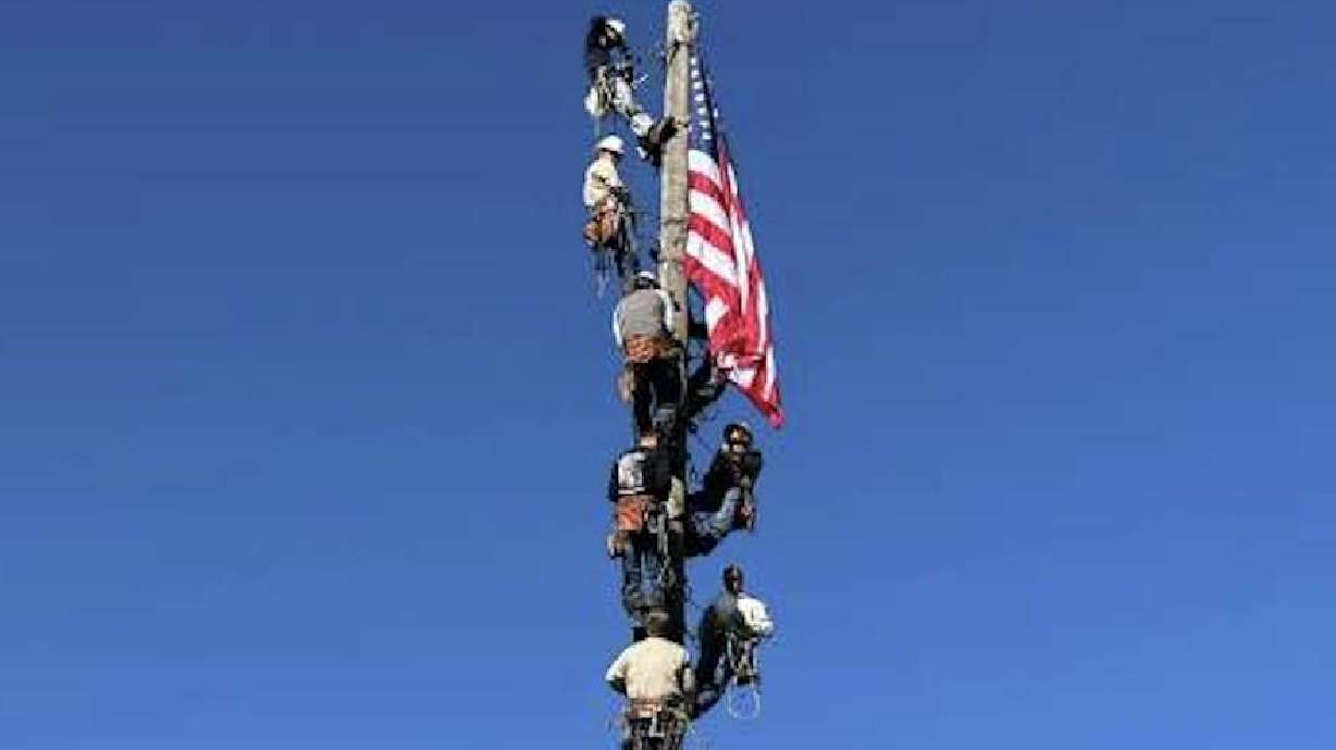 Linemen help hang up the American flag during the flag ceremony at the beginning of the rodeo's event on June 8 in Brigham City.