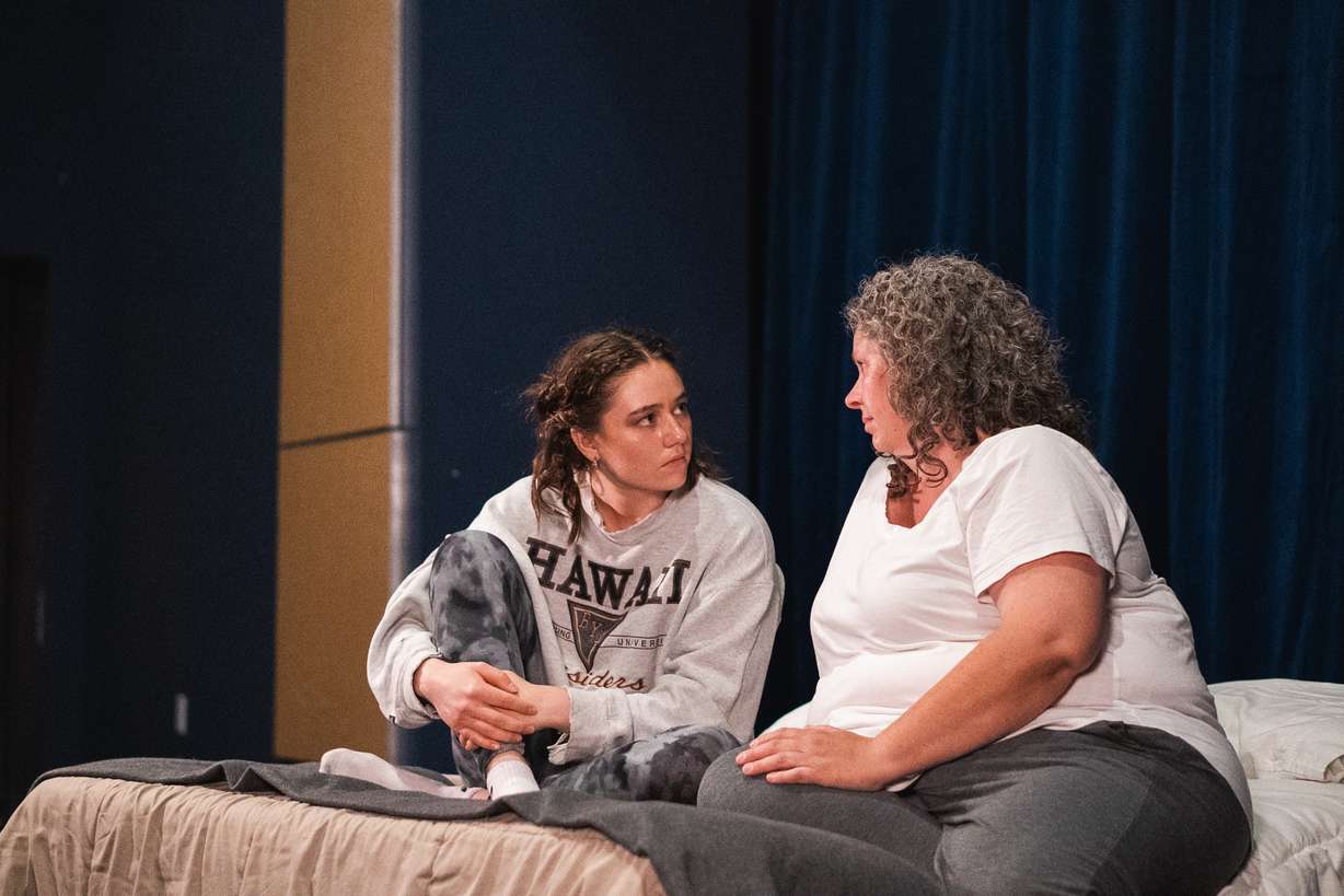 Liz Golden and Leah Carr talk on a bed during a rehearsal for "Relative Space: An Atypical Musical" on May 13. The show depicts mental health challenges in a rock concert theatrical drama that will debut in Pleasant Grove.
