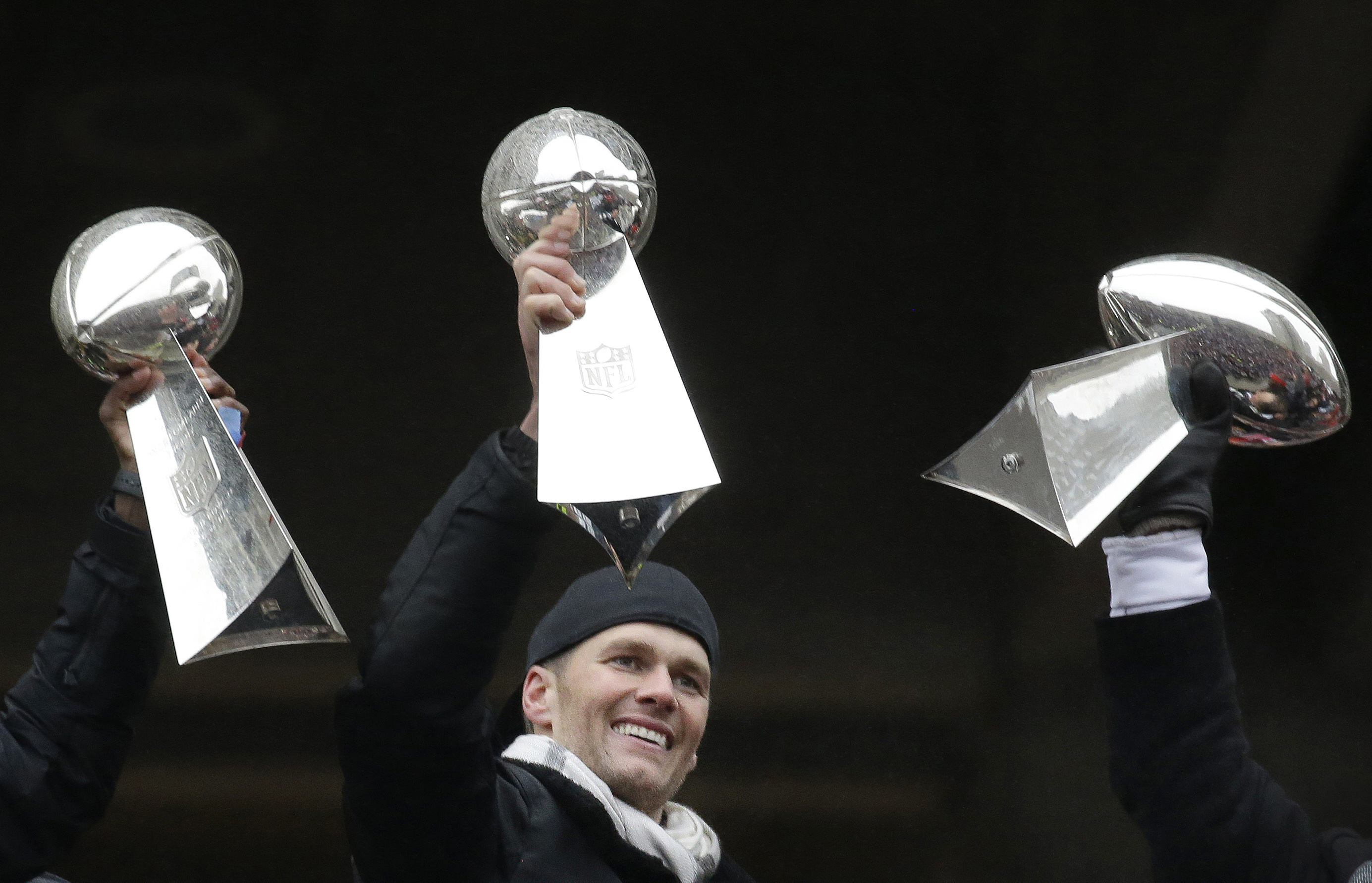 FILE - Then-New England Patriots quarterback Tom Brady holds a Super Bowl trophy, between others the team previously had won, during a rally in Boston to celebrate the team's 34-28 win over the Atlanta Falcons in the NFL Super Bowl 51 football game in Houston, Feb. 7, 2017. The seven-time Super Bowl champion is enjoying retirement while staying busy. He’s preparing for his new 2024 broadcasting gig at Fox Sports, is set to become a minority owner of the Las Vegas Raiders, and is focusing on his apparel and wellness brands.