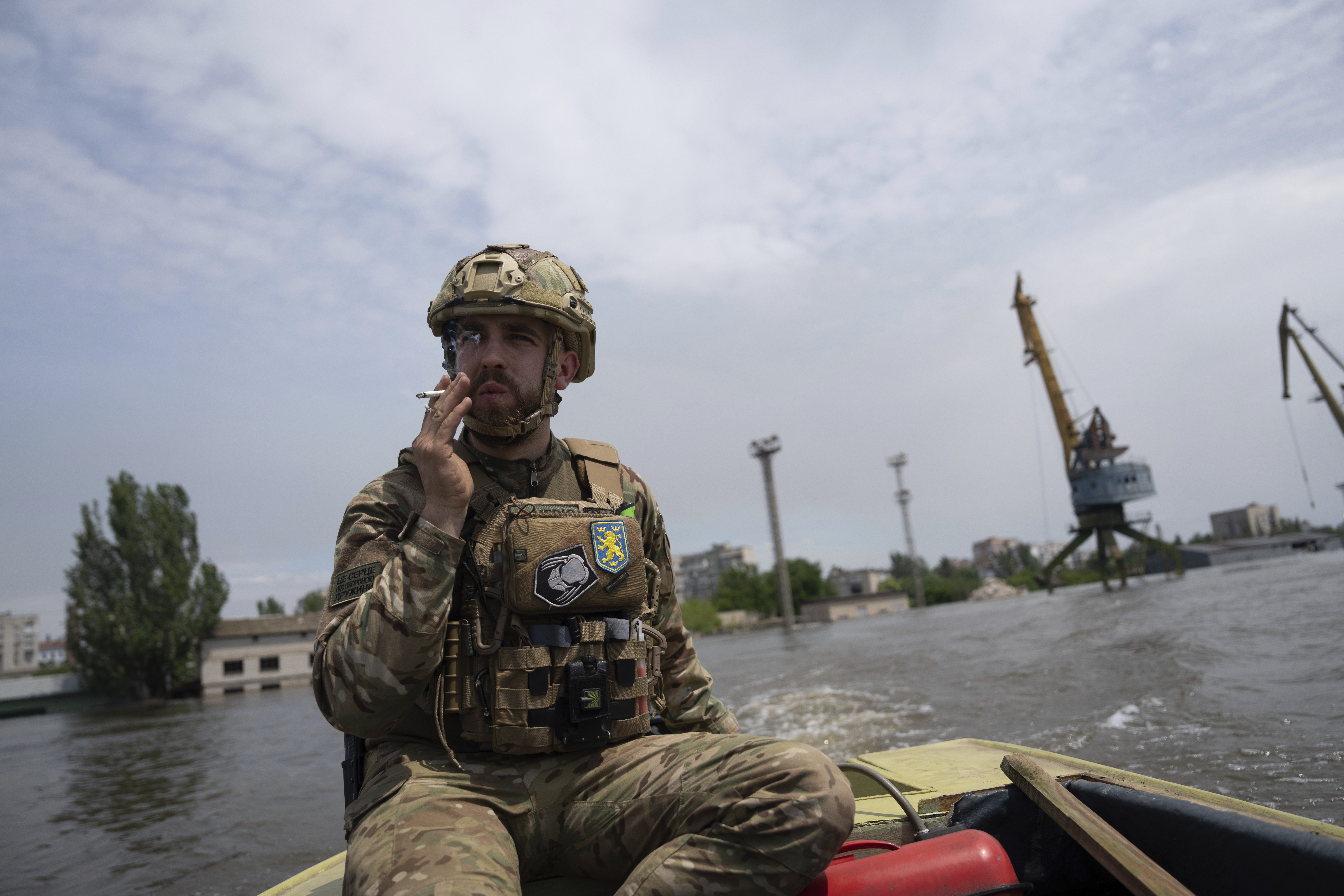 A Ukrainian serviceman steers a boat in a flooded neighborhood in Kherson, Ukraine, Thursday. Floodwaters from a collapsed dam kept rising in southern Ukraine on Wednesday, forcing hundreds of people to flee their homes.