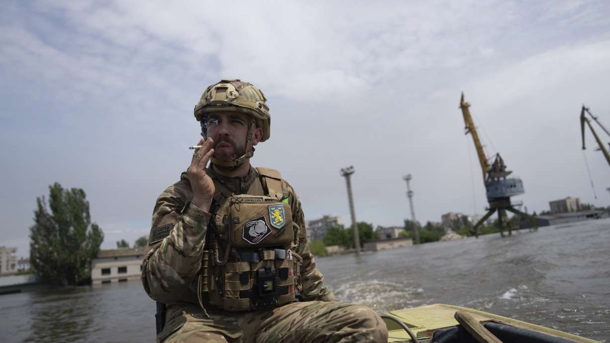 A Ukrainian serviceman steers a boat in a flooded neighborhood in Kherson, Ukraine, Thursday. Floodwaters from a collapsed dam kept rising in southern Ukraine on Wednesday, forcing hundreds of people to flee their homes.