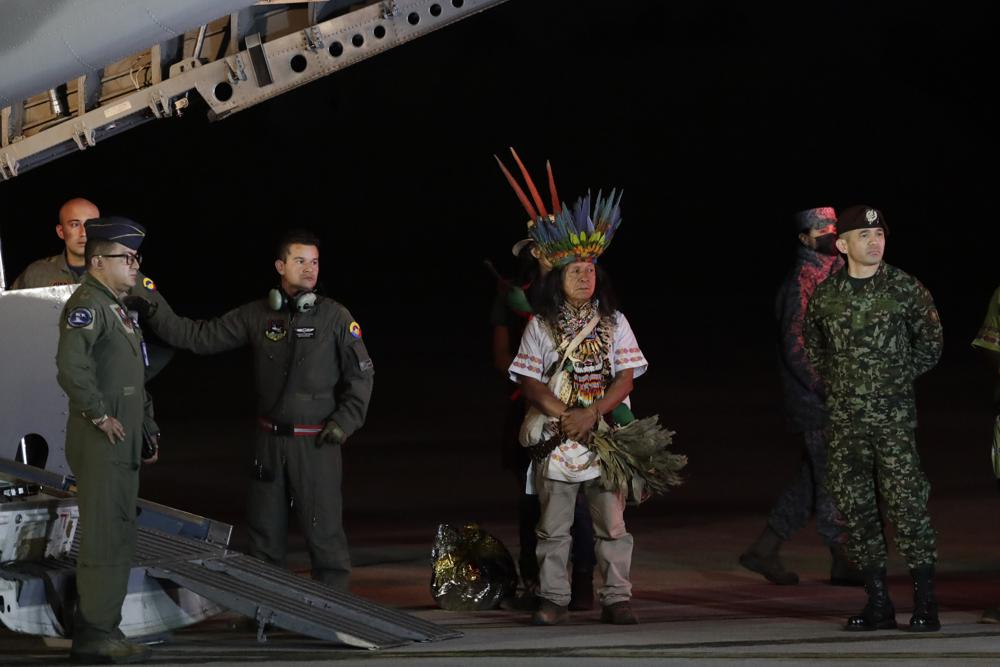 Military personnel and Indigenous leaders stand under a plane after the arrival of four Indigenous children who were missing after a deadly plane crash at the military air base in Bogota, Colombia, Saturday. The children survived a small plane crash 40 days ago and had been the subject of an intense search in the jungle.