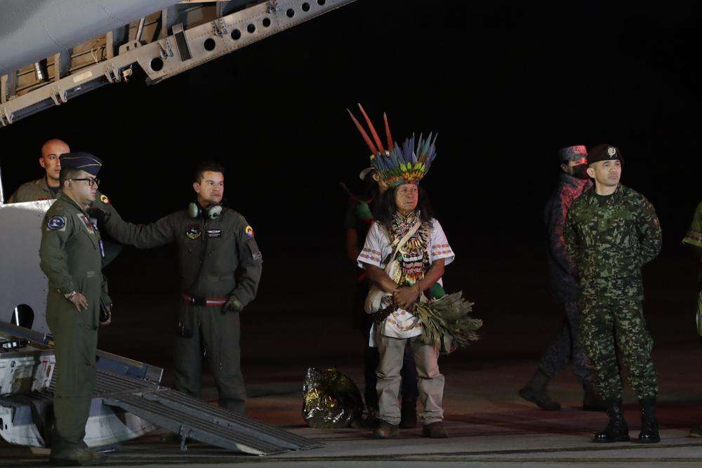 Military personnel and Indigenous leaders stand under a plane after the arrival of four Indigenous children who were missing after a deadly plane crash at the military air base in Bogota, Colombia, Saturday. The children survived a small plane crash 40 days ago and had been the subject of an intense search in the jungle.