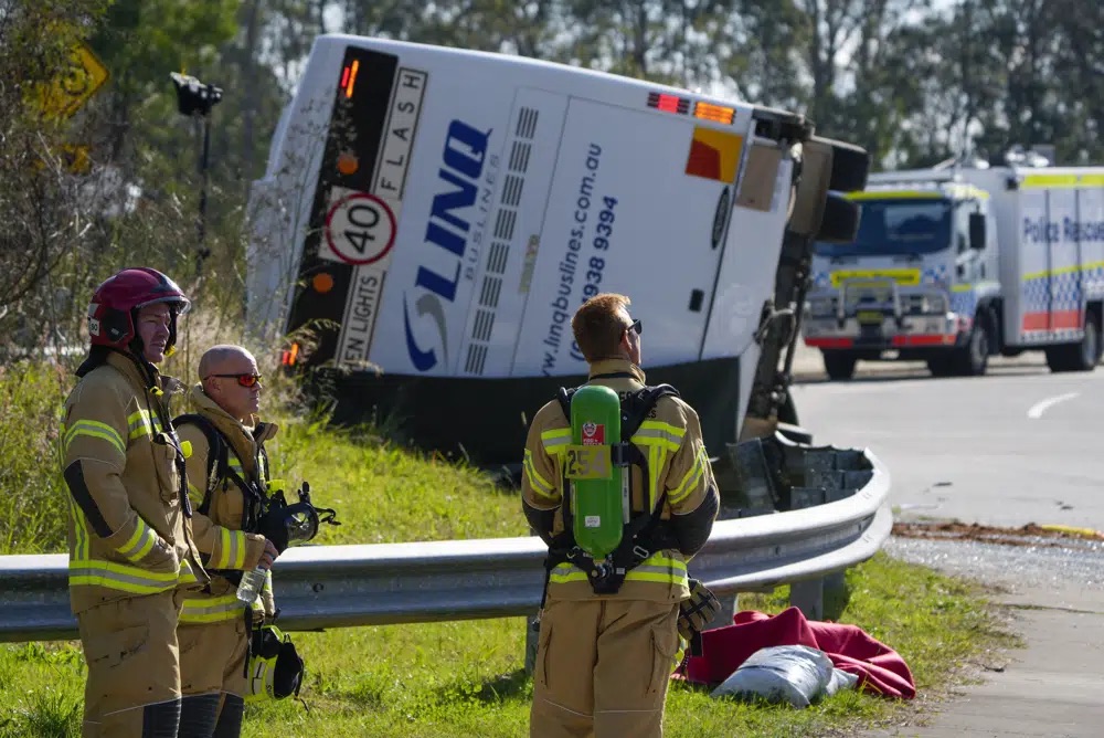 Emergency crews stand near a bus that rolled onto its side near Greta in the Hunter Valley, north of Sydney, Australia, Monday. The bus carrying wedding guests rolled over on a foggy night in Australia's wine country, killing and injuring multiple people, police said.