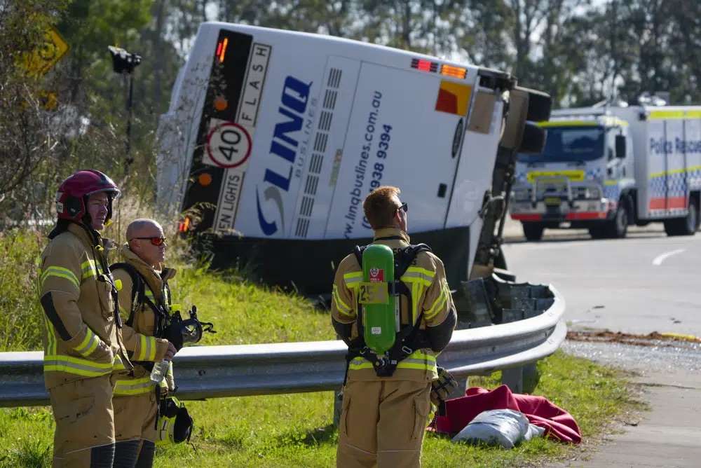 Emergency crews stand near a bus that rolled onto its side near Greta in the Hunter Valley, north of Sydney, Australia, Monday. The bus carrying wedding guests rolled over on a foggy night in Australia's wine country, killing and injuring multiple people, police said.